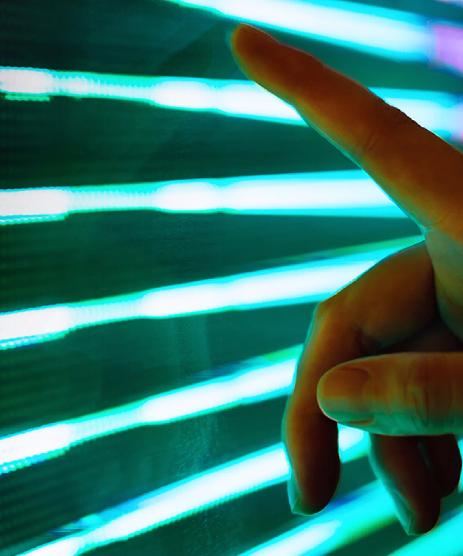 Close-up of a hand reaching out to interact with a vibrant LED light display, symbolizing the connection between technology and human interaction.