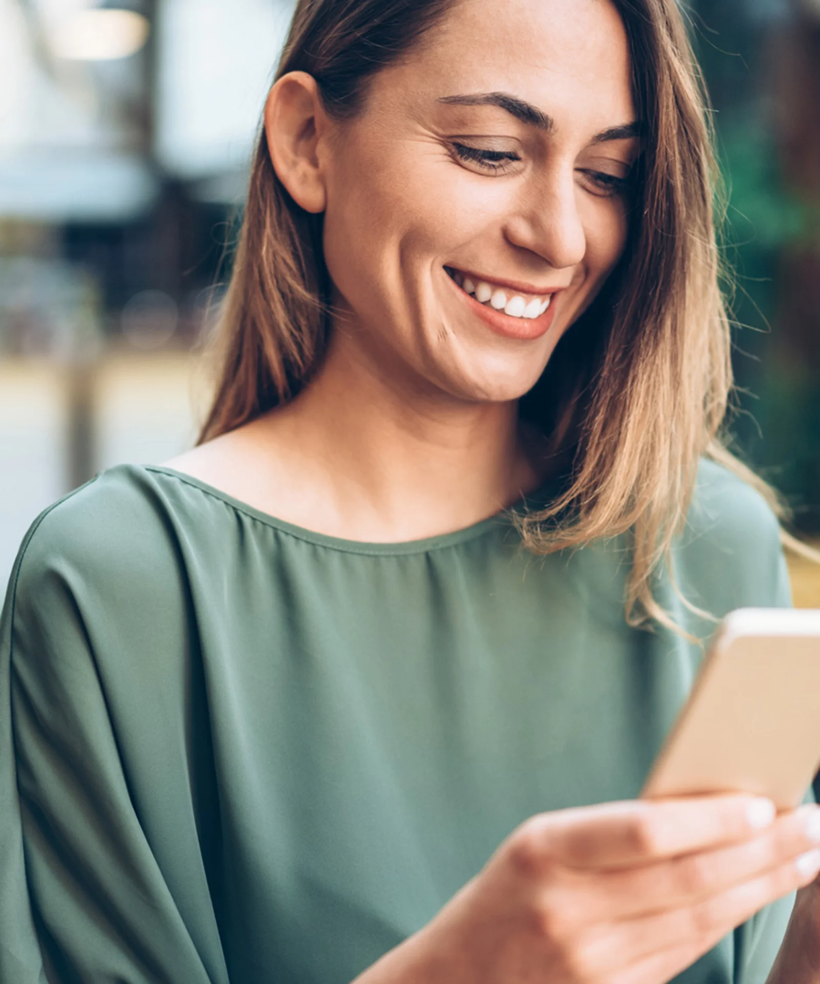 Una mujer sonriente usa un teléfono inteligente y sostiene una tarjeta de crédito, lo que representa la conveniencia de una nueva aplicación móvil de banca comercial.