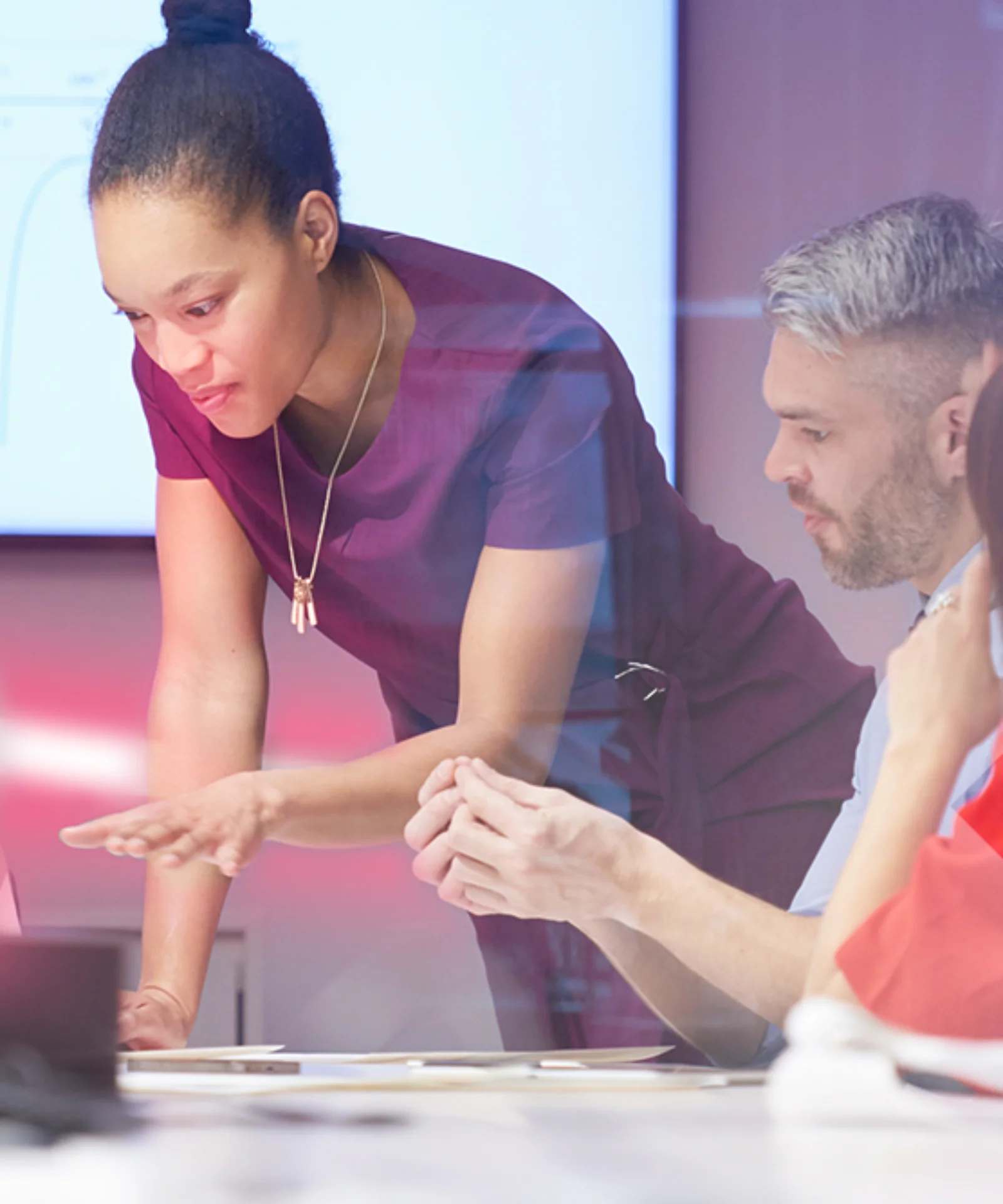 Un grupo de profesionales colaboran durante una reunión estratégica, con el foco puesto en la transformación del core bancario y la agilidad digital. La imagen muestra efectos de iluminación dinámicos y un entorno de oficina moderno.