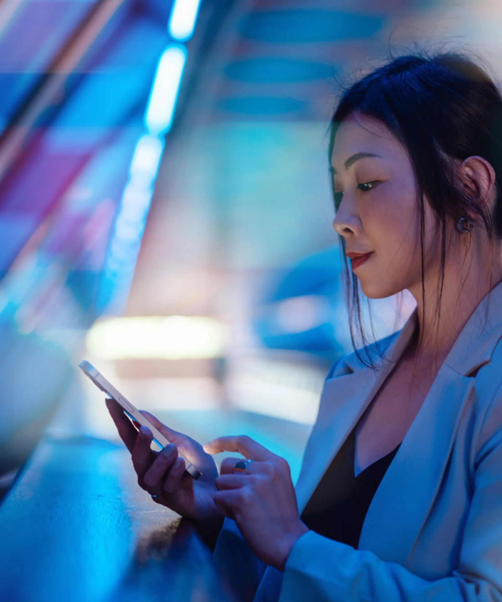 A woman in a business suit uses her smartphone, surrounded by vibrant, abstract digital colours, symbolising the connected and dynamic nature of digital banking.