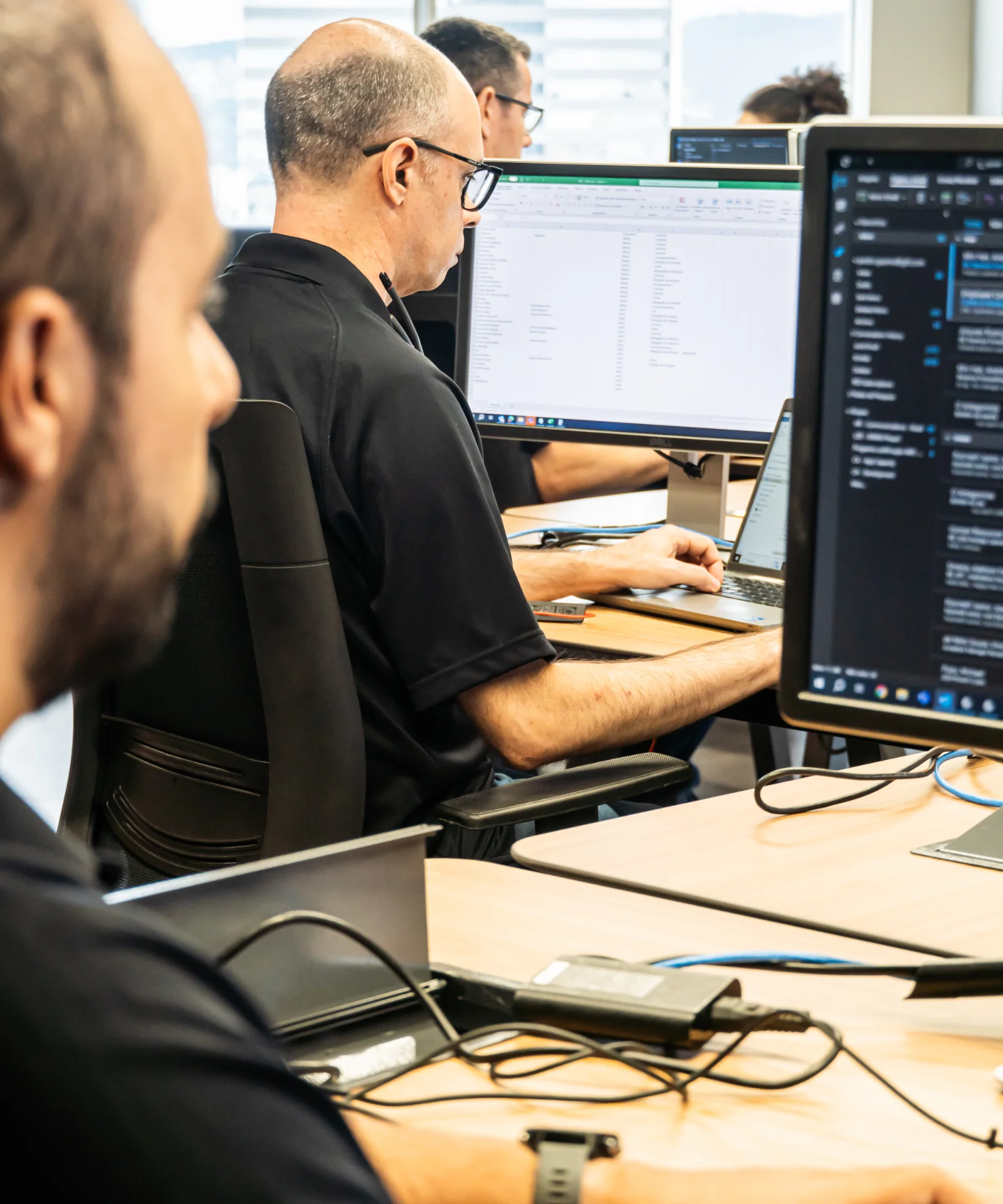 Group of software developers focused on coding at their workstations in a modern office environment.