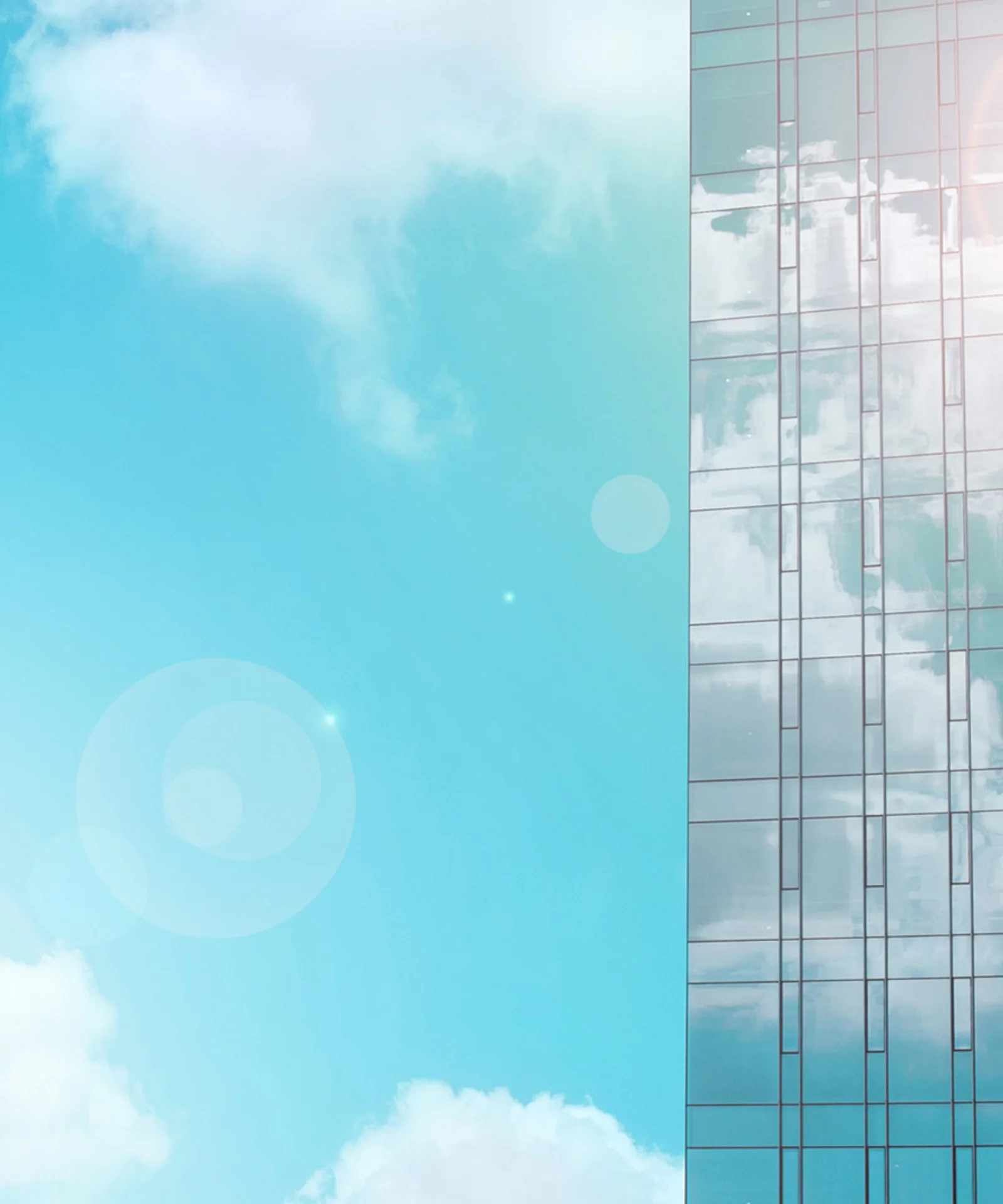 A modern glass skyscraper reflecting a bright blue sky with soft white clouds, symbolising innovation and growth.