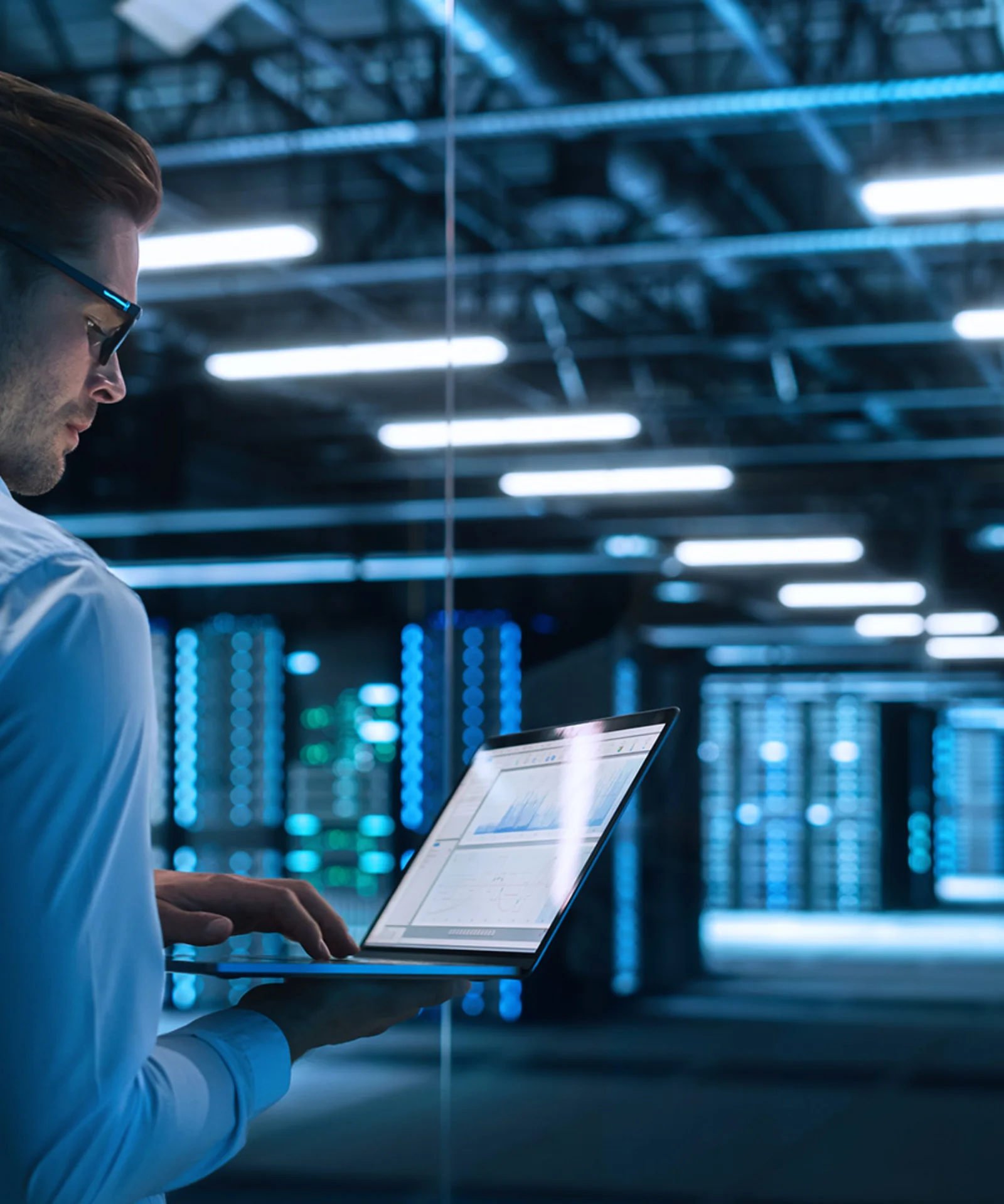 A professional working on a laptop in a high-tech data centre, symbolising the concept of data virtualisation and modern data management solutions.