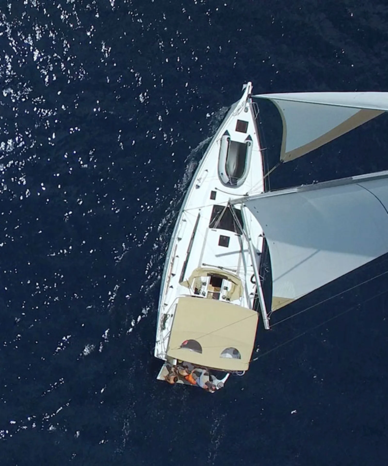 Aerial view of a white sailboat gliding on deep blue water, representing the innovative and smooth sailing solutions of BankLiteX.