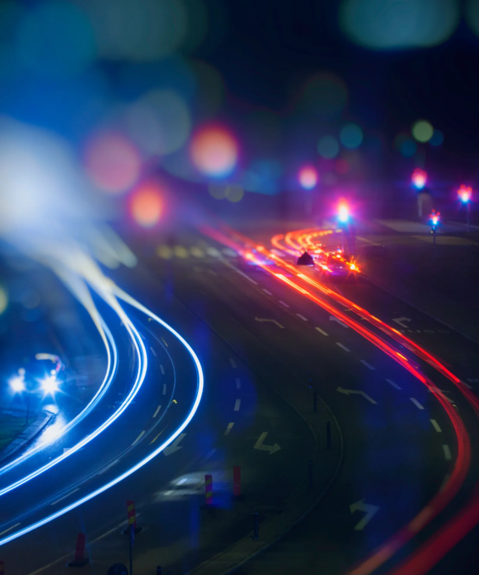 A night scene capturing dynamic light trails from vehicles on a city road, symbolising speed and movement.