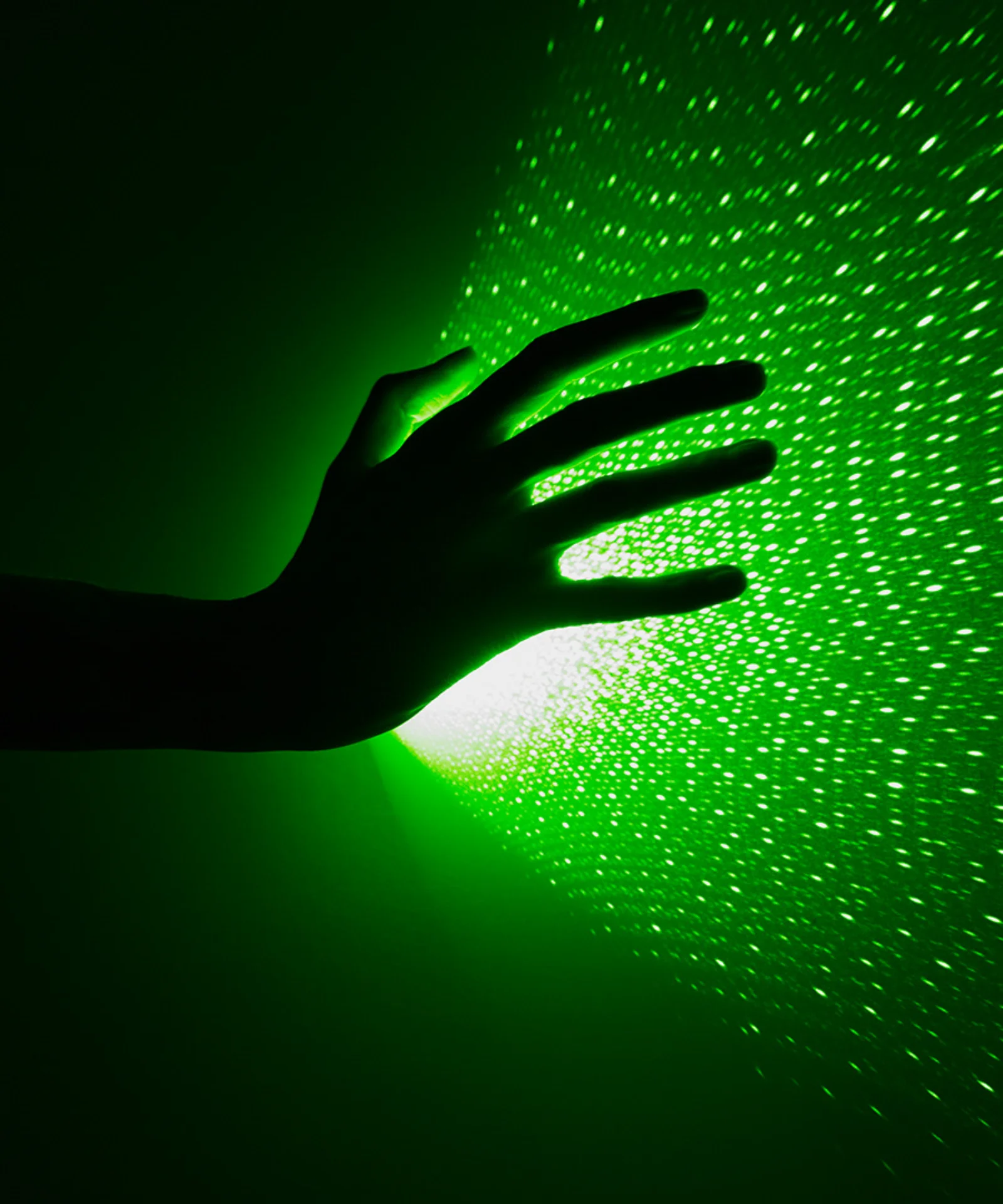 A hand reaching towards a green light, symbolizing the exploration of sustainable color palettes in design and technology.