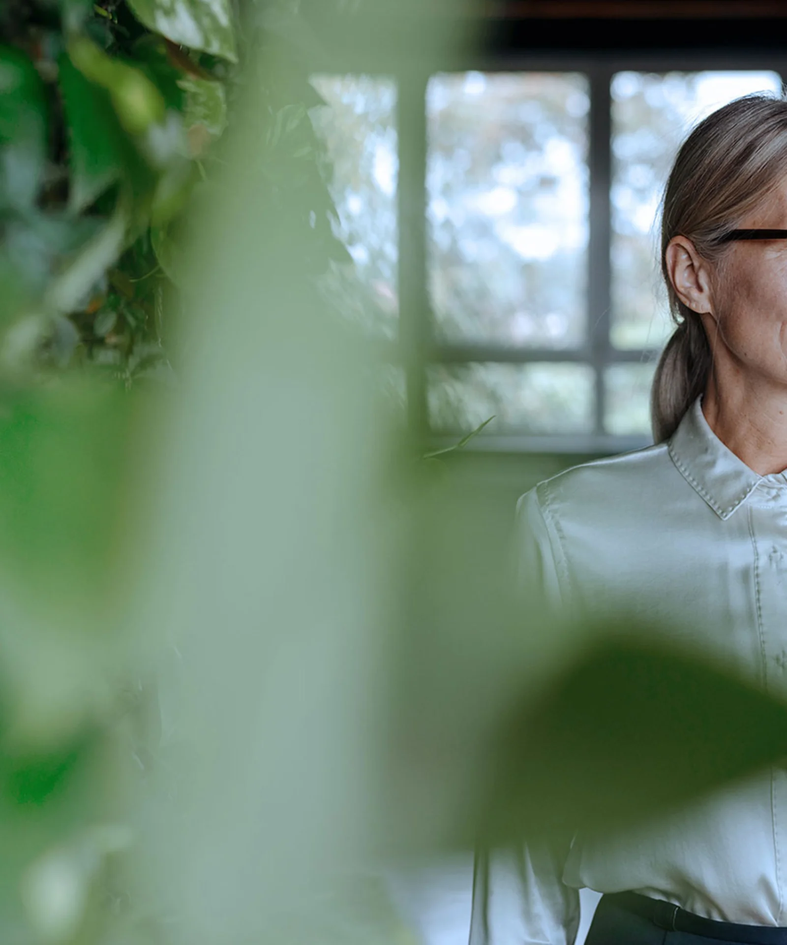 A confident professional woman in a light blouse, surrounded by greenery, symbolising CSR governance and leadership in sustainability