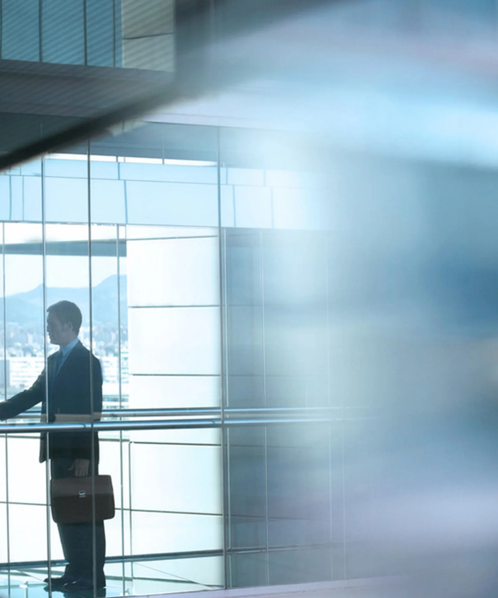 Two business professionals shaking hands in a modern office building with large glass windows, symbolising trust and successful partnership.