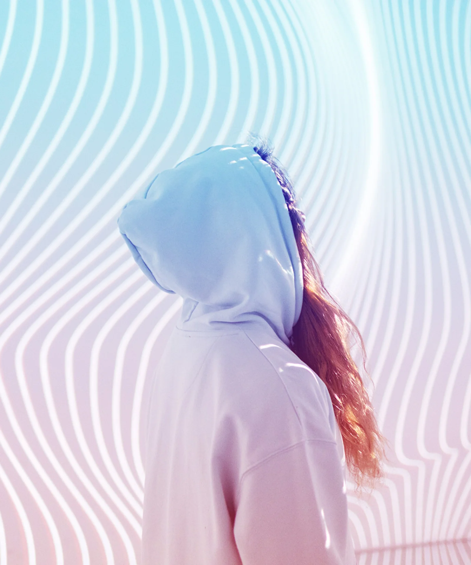 A person in a hooded sweatshirt standing in front of a modern, abstract background with flowing lines and vibrant colours, symbolising the innovative transformation in the insurance industry through mainframe modernisation.