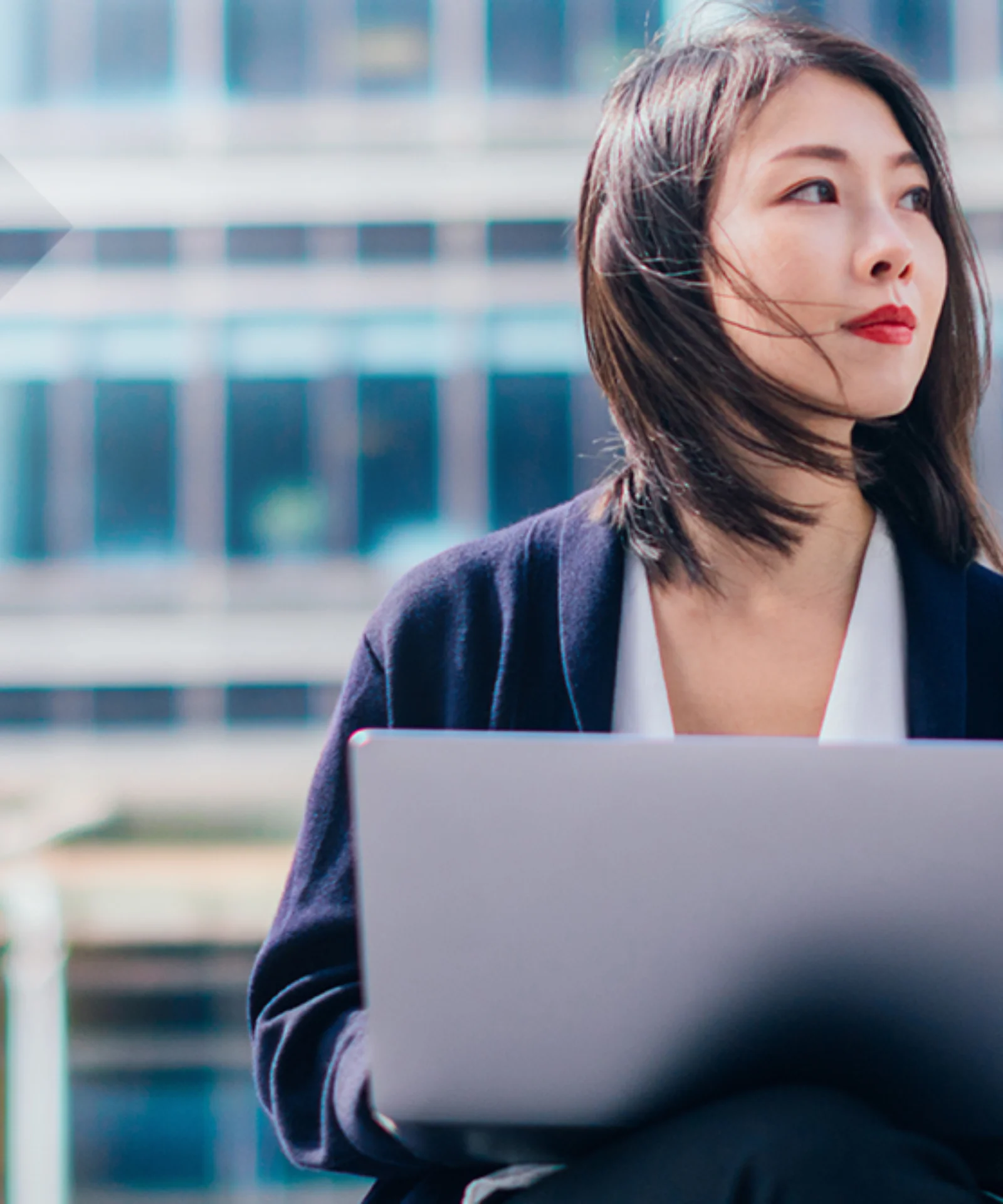 Headerbild einer Geschäftsfrau mit Laptop vor einem modernen Bürogebäude. Symbolisiert die T+1-Roadmap und die digitale Transformation der Finanzmärkte in Europa.