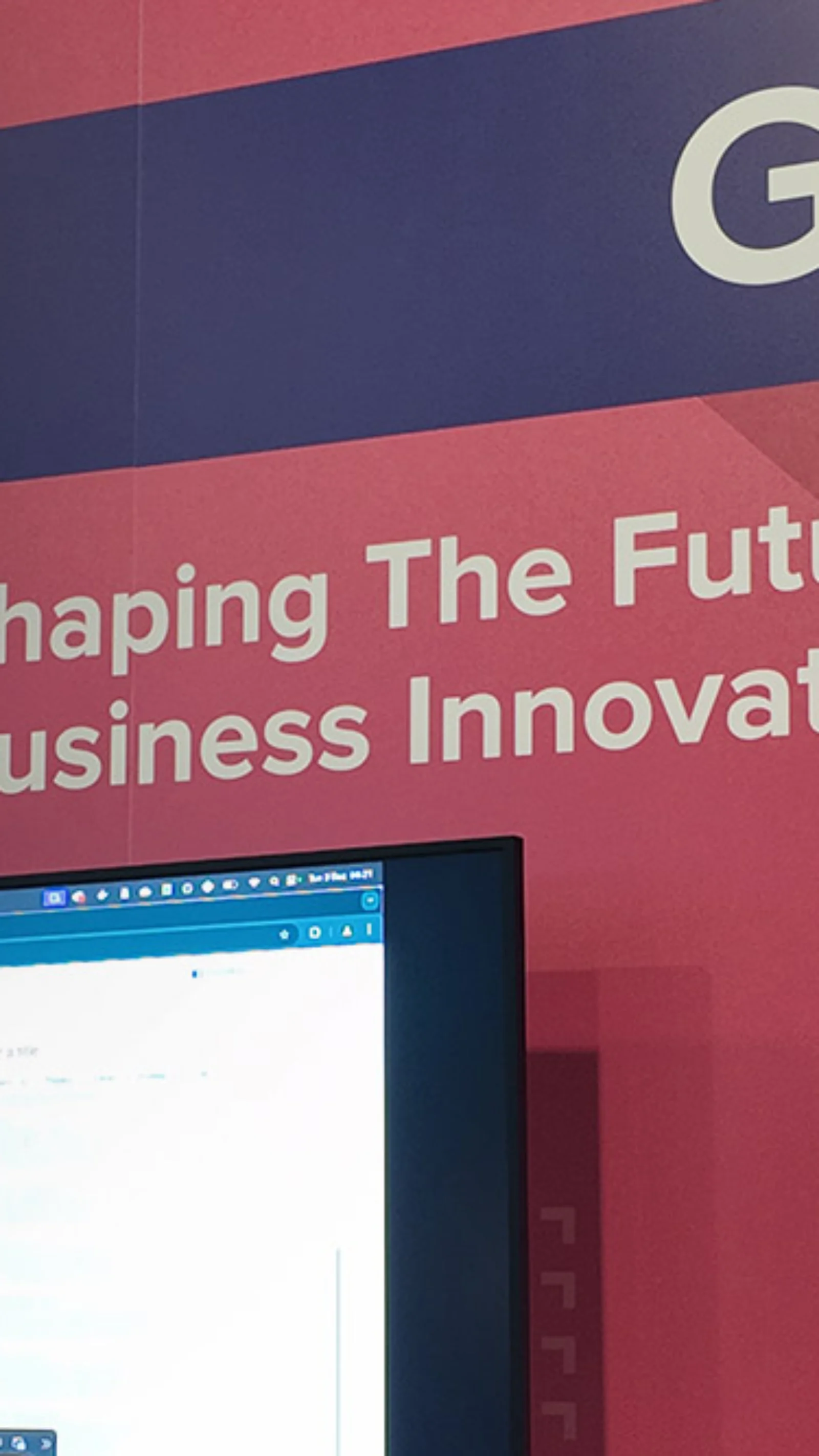 GFT exhibition booth with a banner reading &quot;Shaping the Future of Business Innovation,&quot; highlighting services such as Generative AI, Platform Modernization, and Visual Inspection. Two individuals are interacting with a screen showcasing GFT technology solutions.