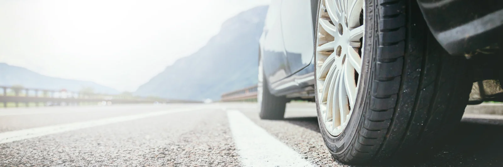 Close-up of a car wheel on an open road, symbolising the seamless process of searching, financing, and driving away with a new vehicle.