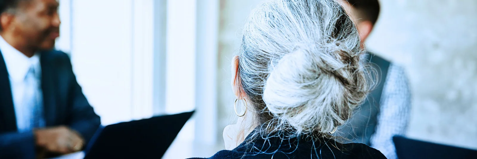 Key visual for investor relations showing a diverse business meeting with a focus on a woman with grey hair in a bun.