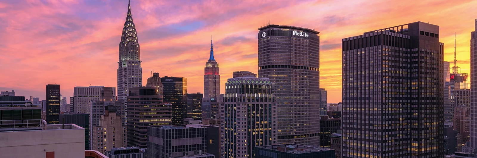 A vibrant sunset over the New York City skyline, featuring iconic skyscrapers such as the Chrysler Building and the MetLife Tower.