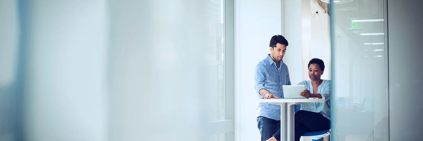 Two professionals collaborating on a laptop in a modern office setting