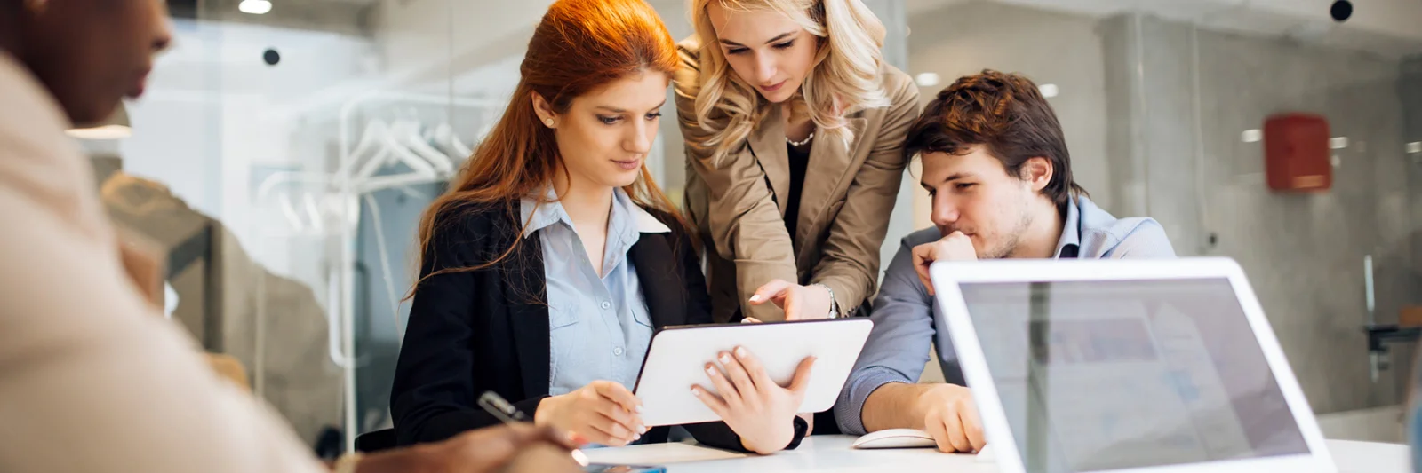 Group of professionals discussing business workflow improvements using a digital tablet in a modern office setting.