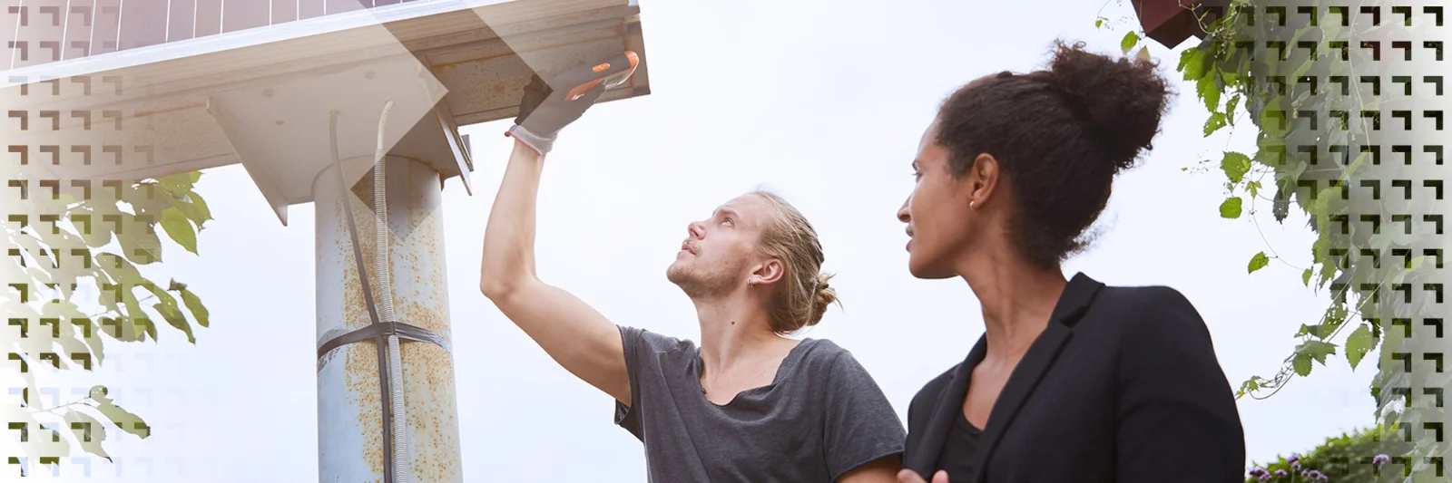 Two professionals collaborating during the installation of a solar panel, with one inspecting the panel and the other observing.