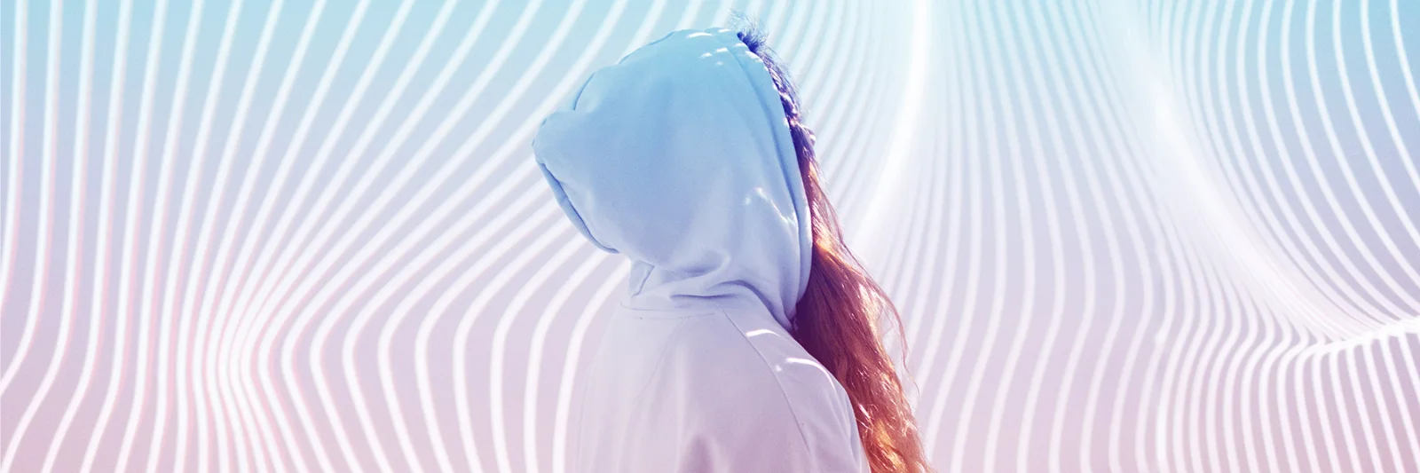 A person in a hooded sweatshirt standing in front of a modern, abstract background with flowing lines and vibrant colours, symbolising the innovative transformation in the insurance industry through mainframe modernisation.