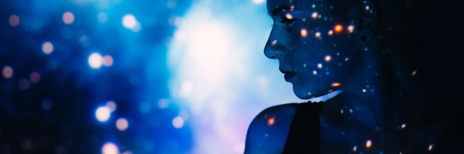 A silhouetted profile of a person with a digital starry projection on their face and background, symbolising the power and creativity of artificial intelligence.