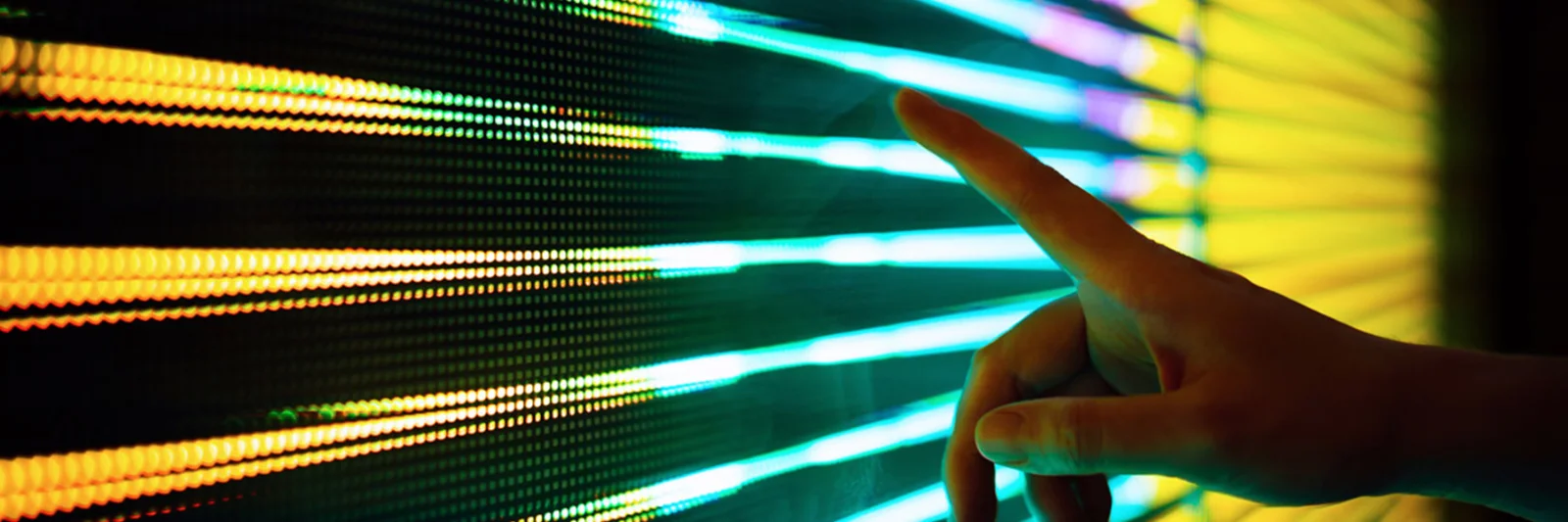 A hand interacting with a vibrant LED digital interface, showcasing dynamic data or light patterns.