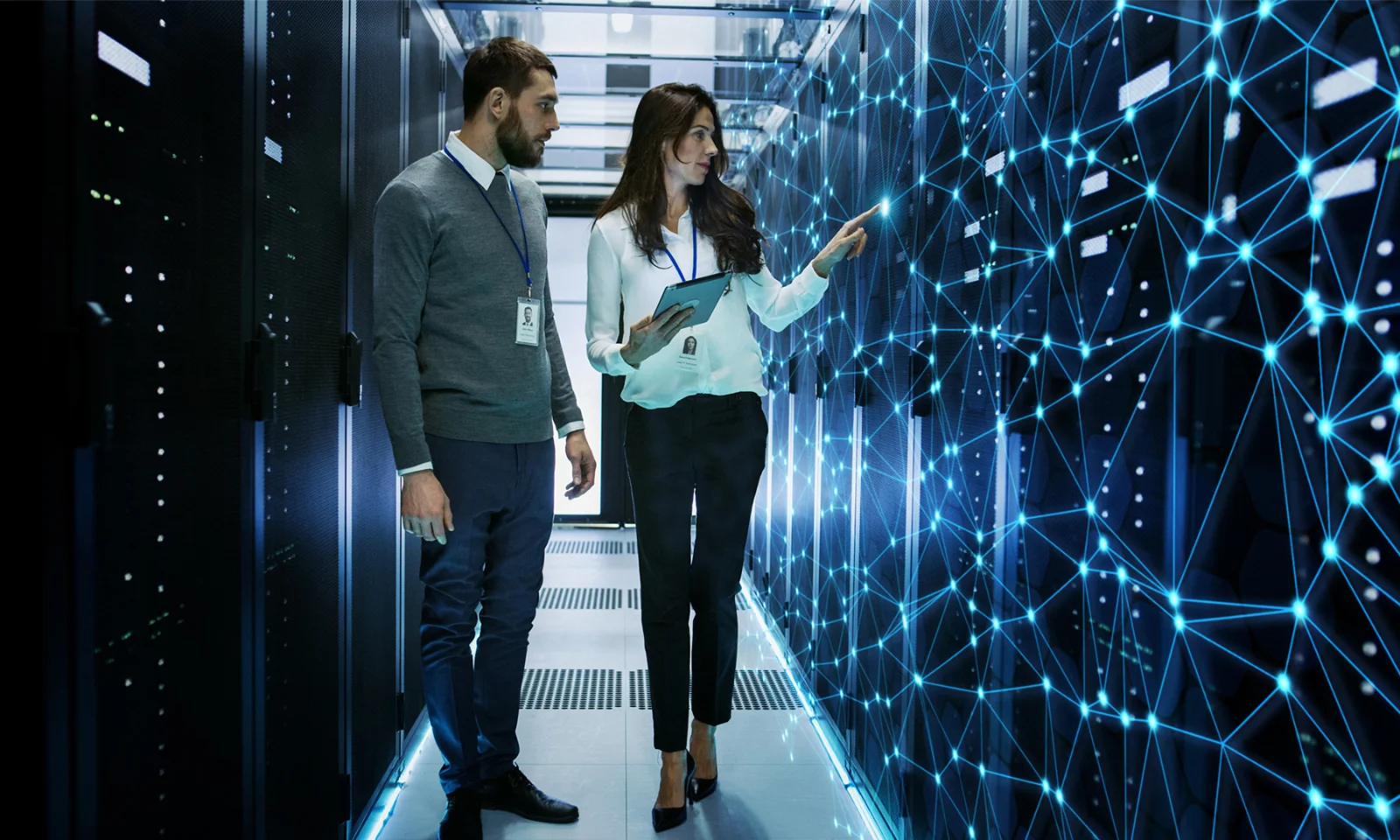 Two professionals in a data centre discussing and analysing a digital network, representing the implementation of a visionary sales platform.