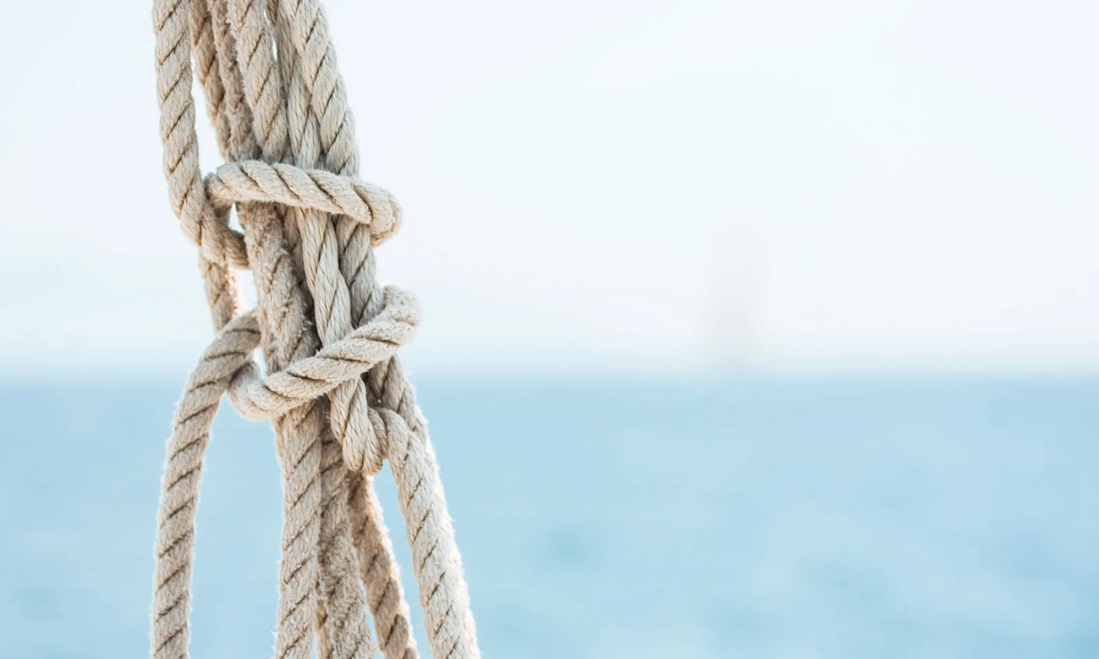 A close-up of a neatly tied nautical rope knot against a backdrop of a calm, blue sea, symbolizing the strength, reliability, and interconnectedness of the BankLiteX solution.