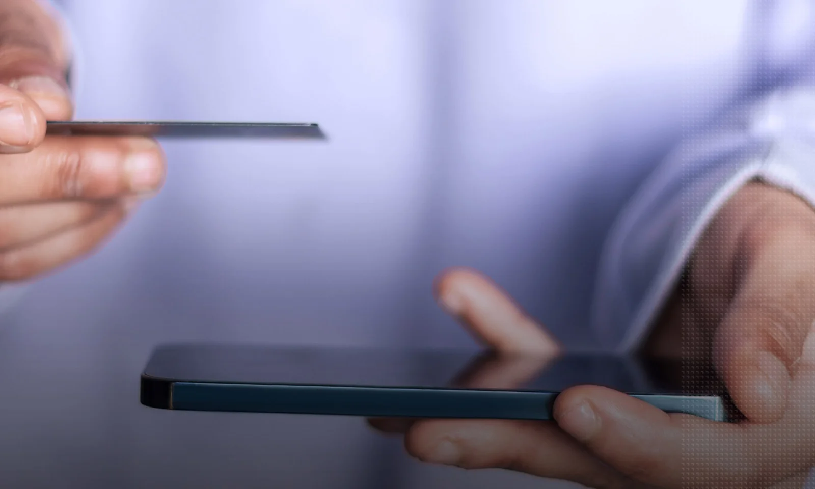 Close-up of hands holding a smartphone and a credit card, symbolizing a mobile payment transaction.