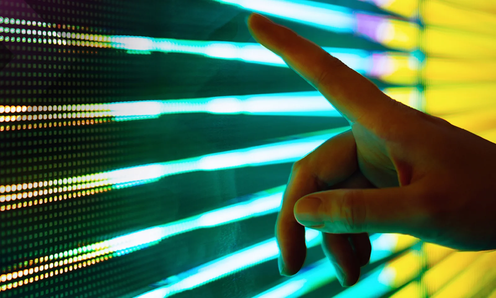 Close-up of a hand reaching out to interact with a vibrant LED light display, symbolizing the connection between technology and human interaction.