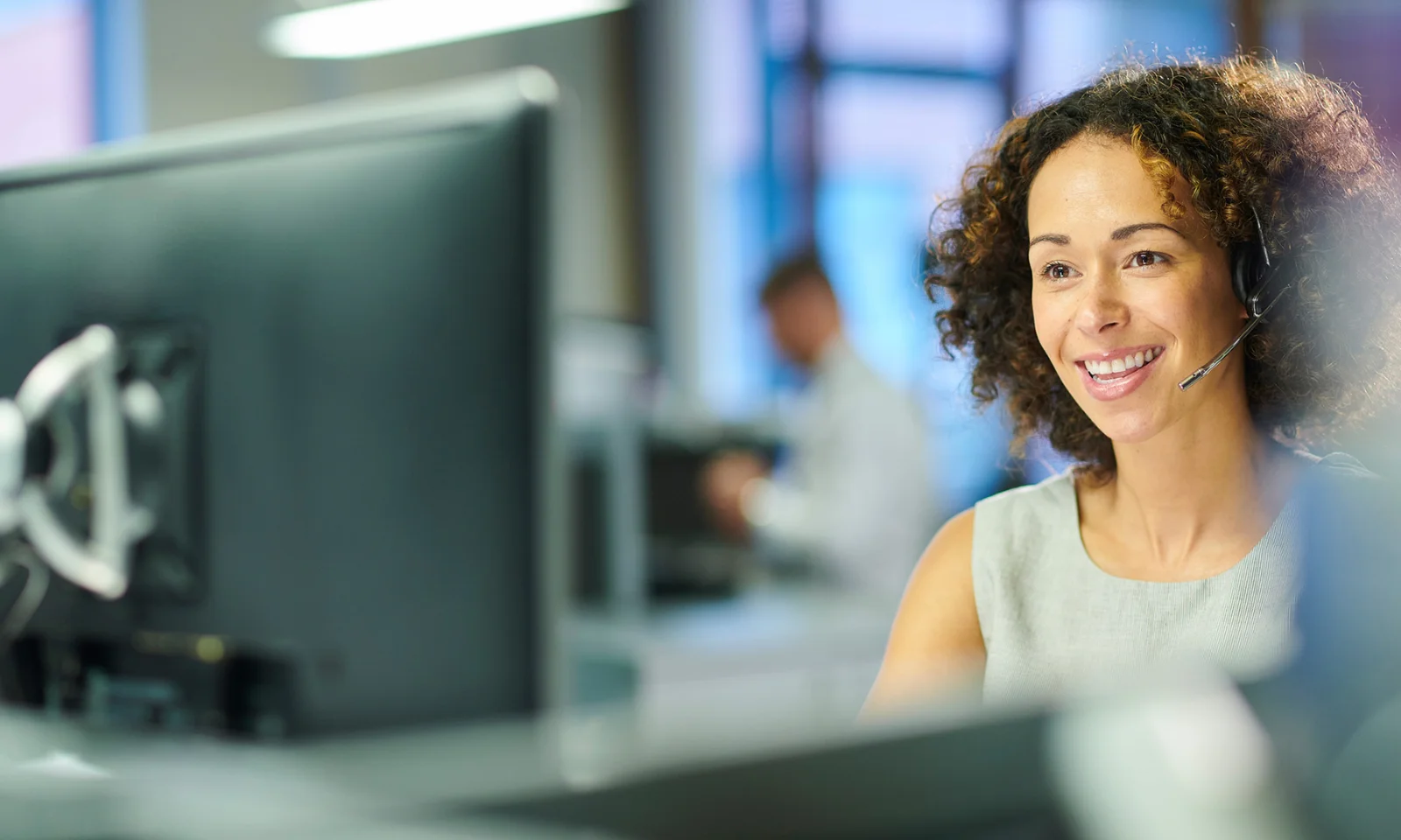 A smiling customer service representative wearing a headset, symbolising the transformation of claims settlement processes through digital solutions.