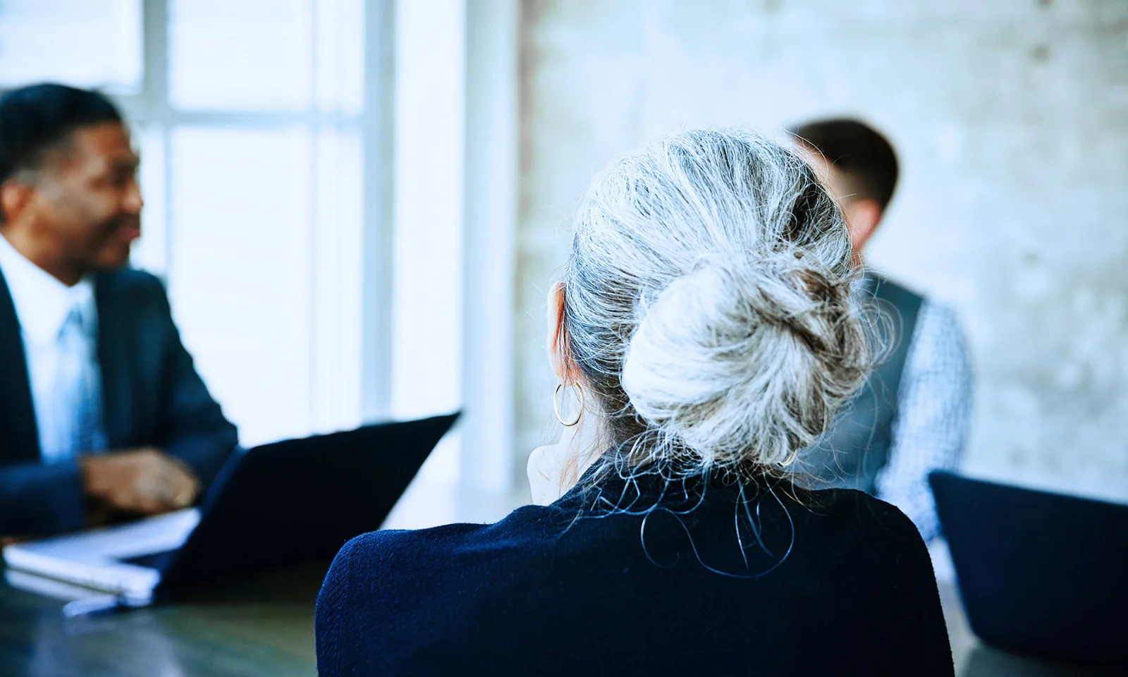 Key visual for investor relations showing a diverse business meeting with a focus on a woman with grey hair in a bun.