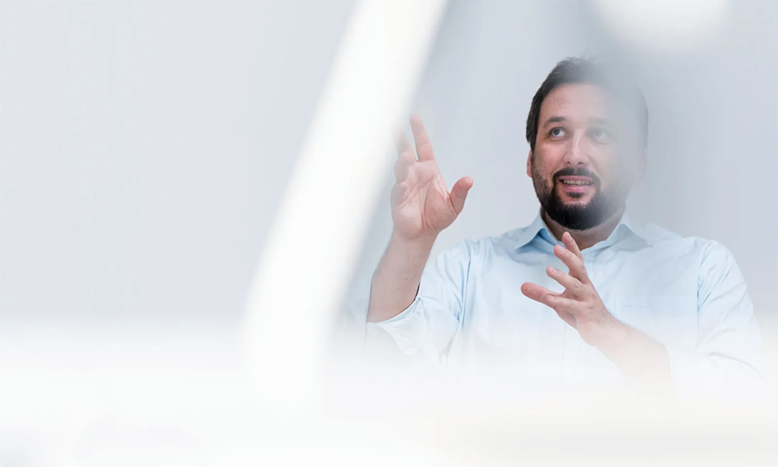 A man in a light blue shirt gestures while discussing ideas, symbolising thought leadership and innovation in the technology sector.