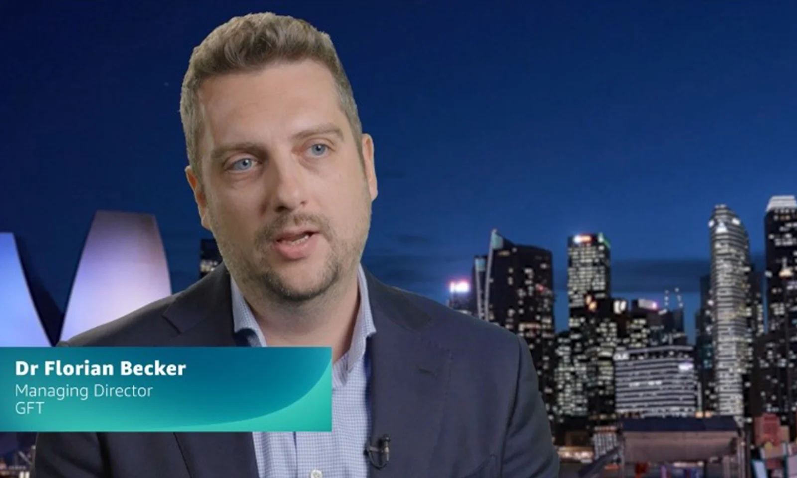 Dr Florian Becker, Managing Director of GFT, speaking against a backdrop of a city skyline at night.