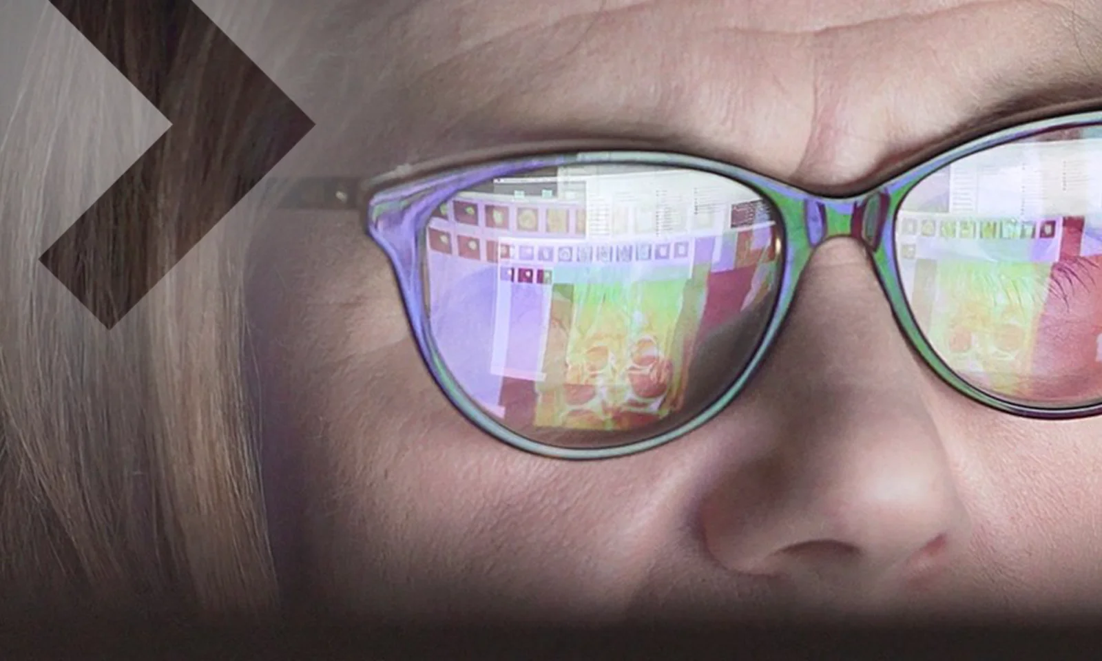 Nahaufnahme einer Frau mit Brille, in deren Gläsern ein Bildschirm mit Bildanalysen reflektiert wird, symbolisierend die Anwendung von visueller Inspektionstechnologie.