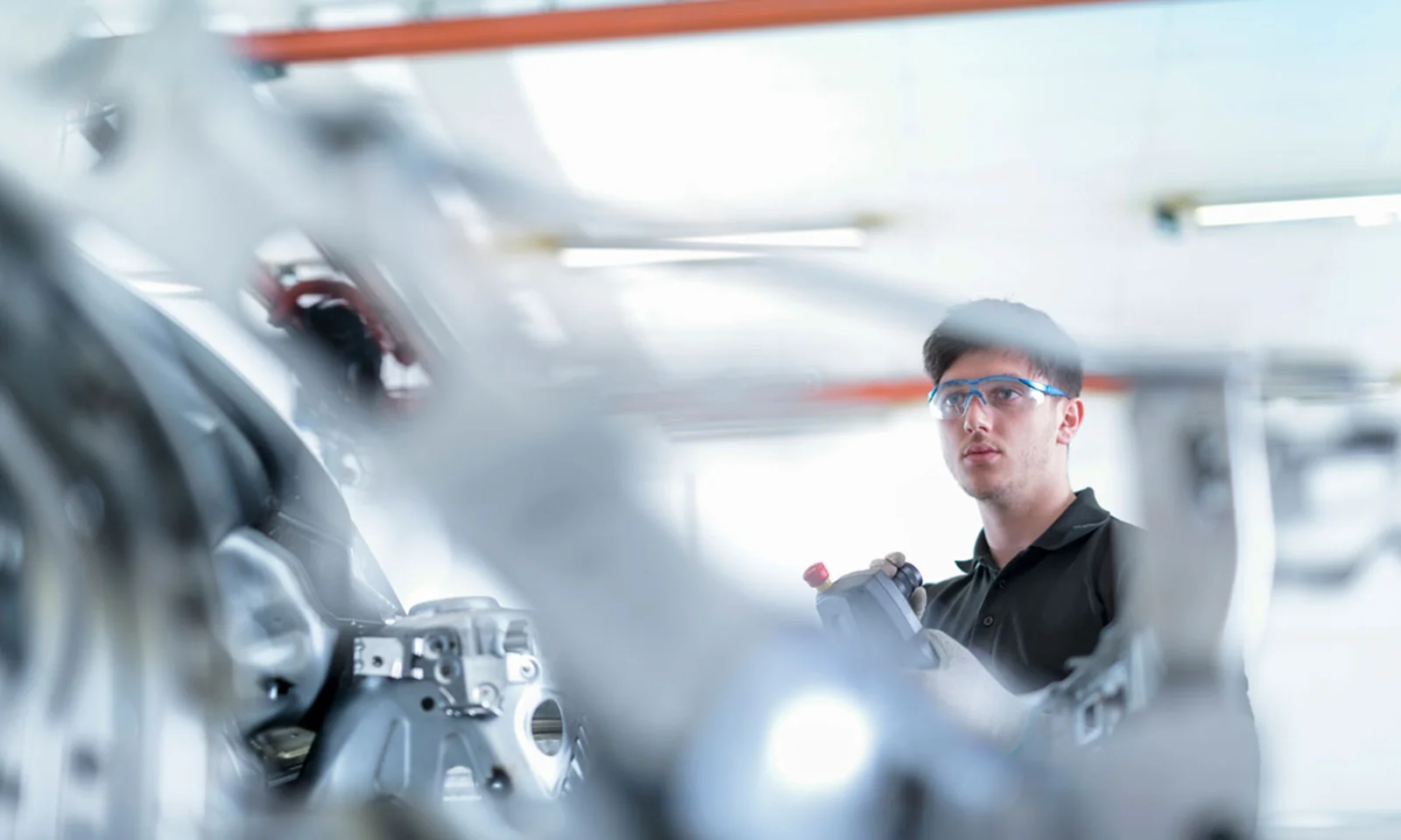 An engineer wearing safety glasses operates advanced machinery in a manufacturing facility, highlighting the integration of IoT technology.