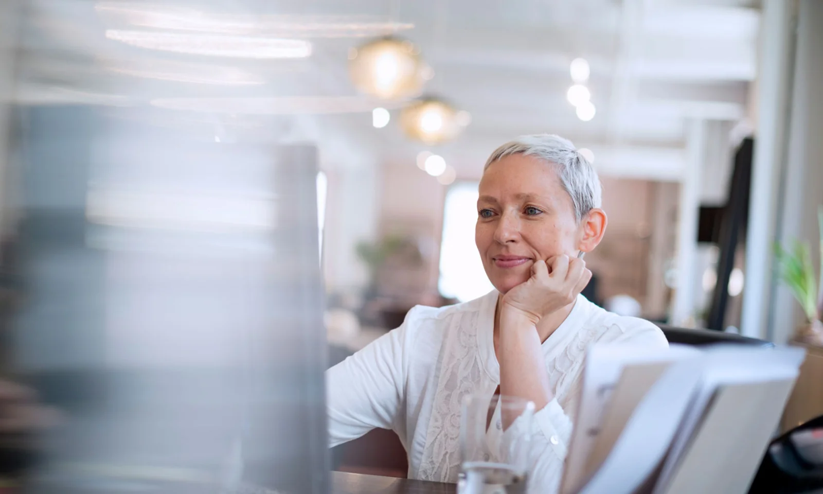 Smiling professional woman working at her desk in an office, representing the transformation of HR with AI chatbots.