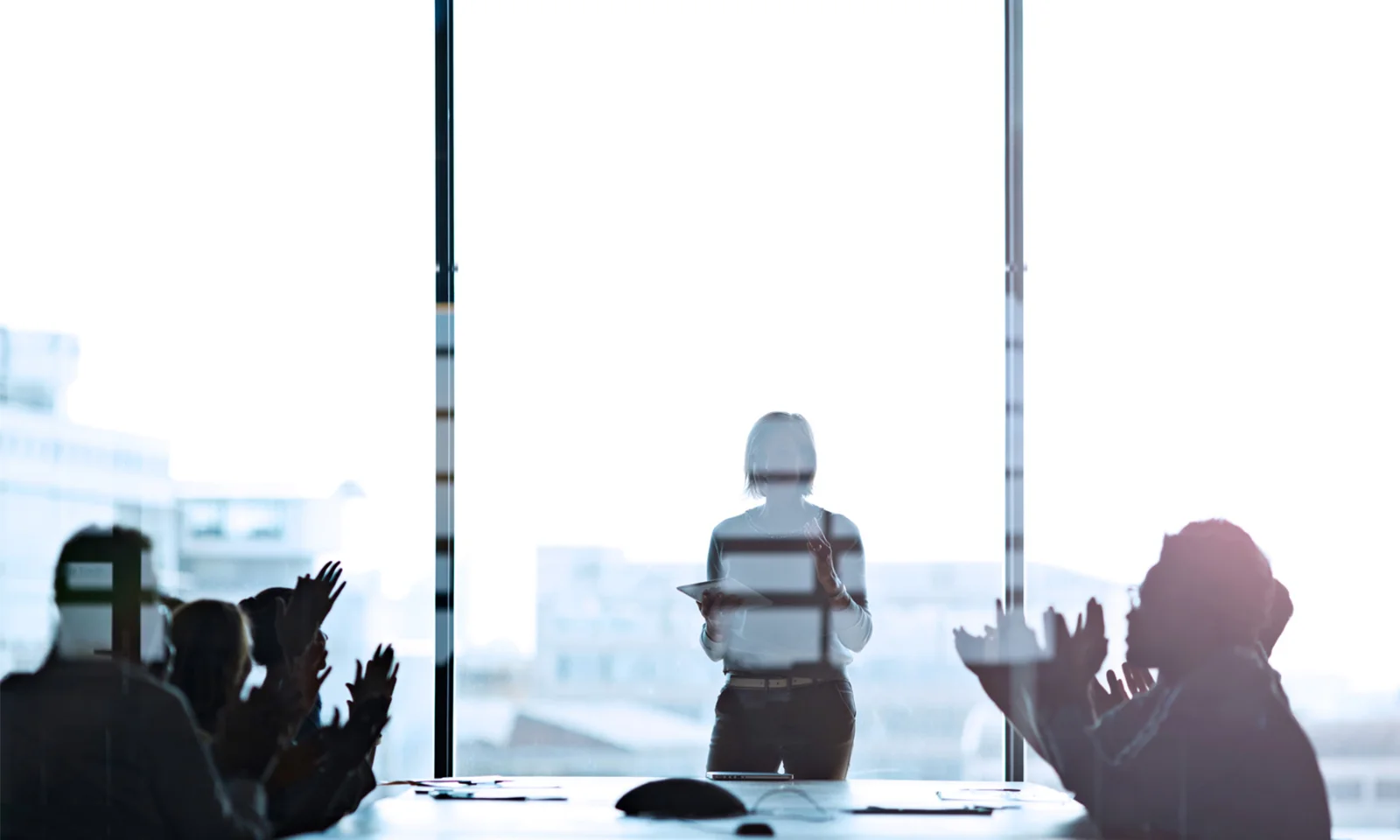 A group of professionals in a modern office, focusing on a woman leading a meeting or presentation, symbolizing leadership and collaboration.