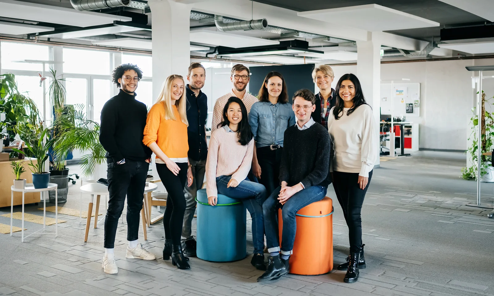 GFT Team Photo - A diverse group of GFT employees standing and sitting in a modern, open office space, showcasing the company&#039;s inclusive and collaborative work culture.