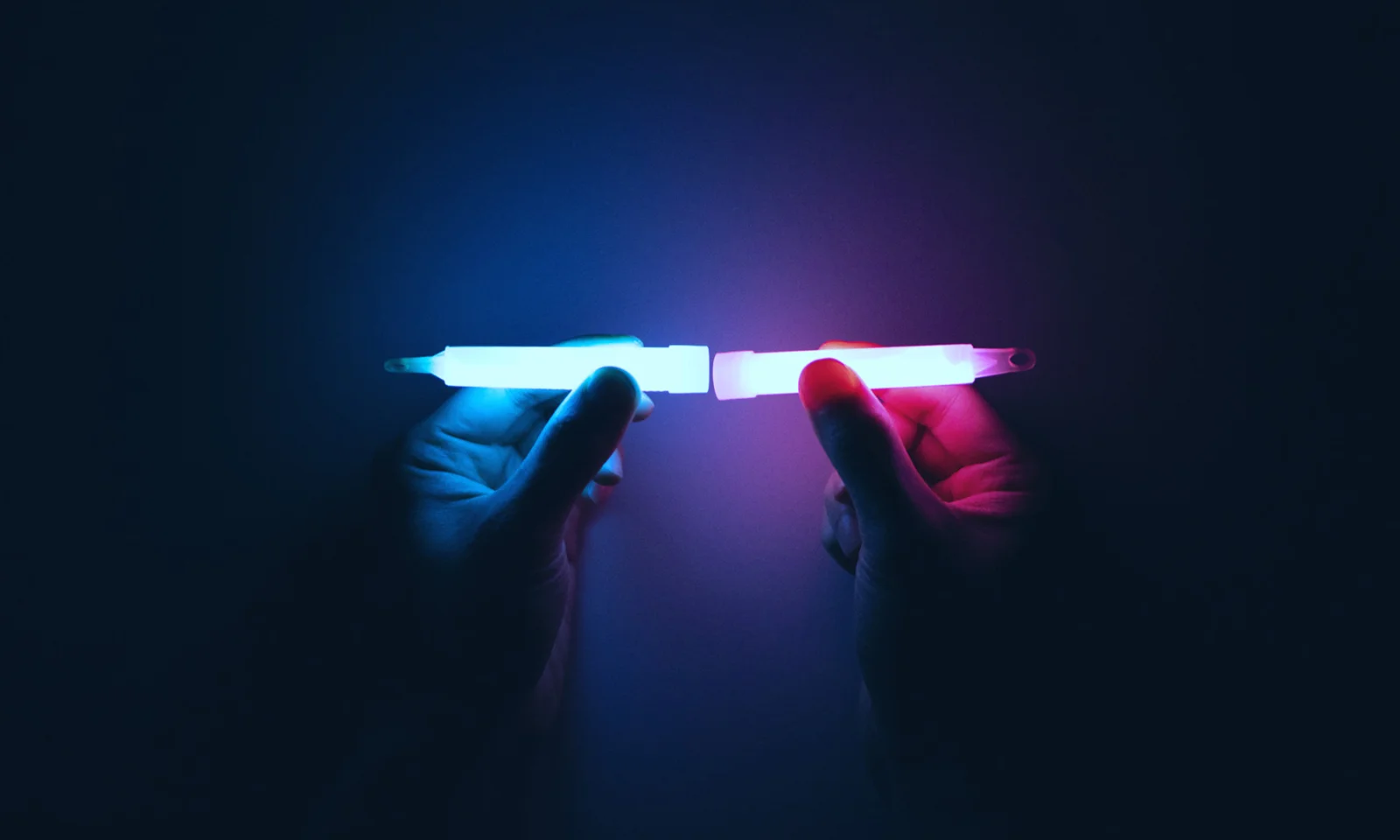 Two hands holding glowing light sticks, one blue and one pink, symbolizing the fusion and connection in platform modernisation.