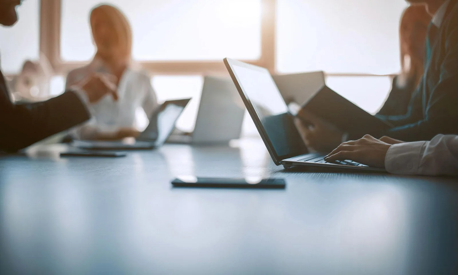 Business professionals working on laptops in a meeting room, focusing on secure and connected AWS cloud solutions.