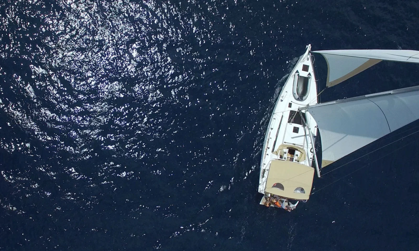 Aerial view of a white sailboat gliding on deep blue water, representing the innovative and smooth sailing solutions of BankLiteX.