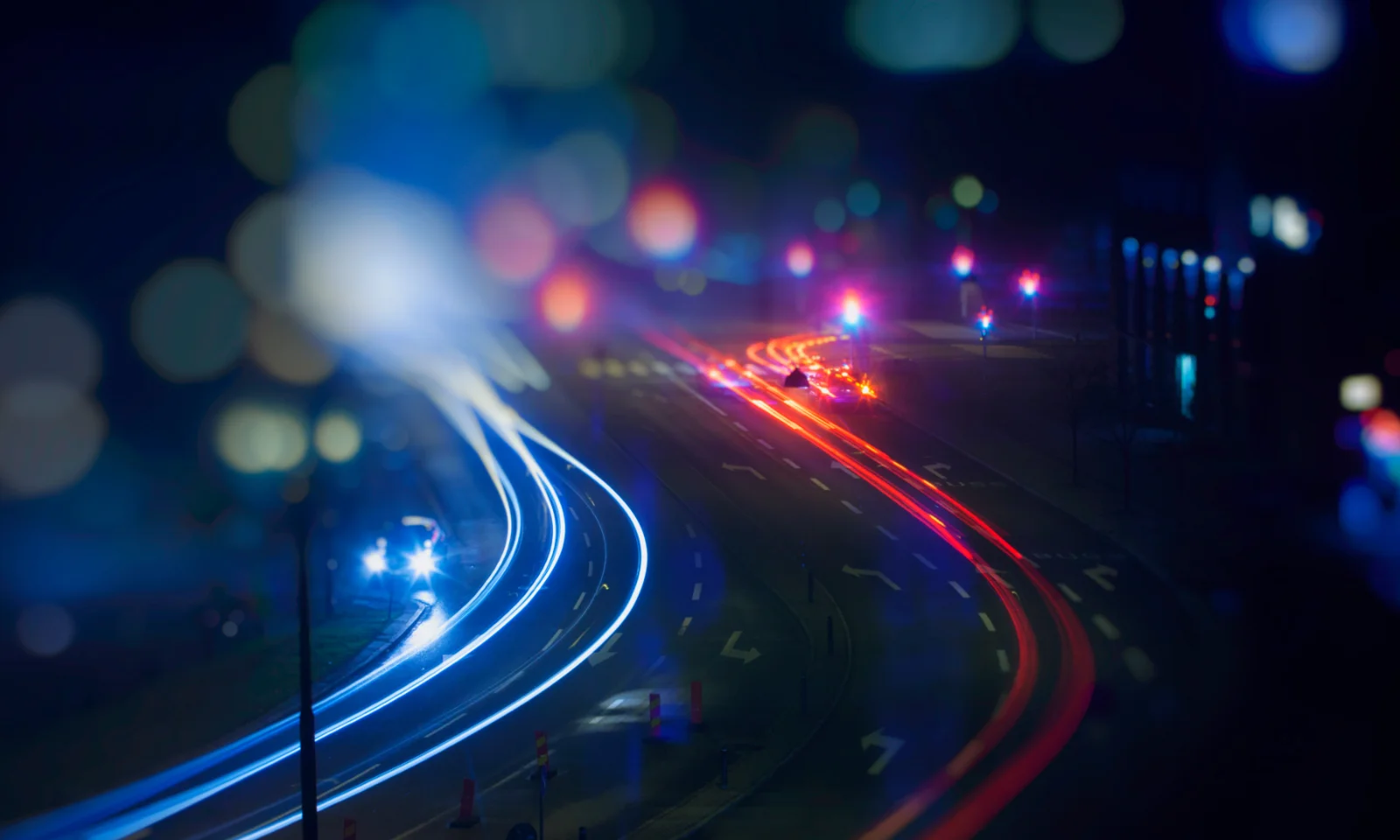 A night scene capturing dynamic light trails from vehicles on a city road, symbolising speed and movement.