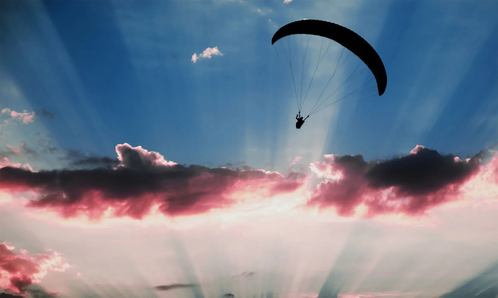 A silhouette of a paraglider soaring against a stunning sunset sky, symbolising the freedom, scalability, and innovation offered by cloud computing.