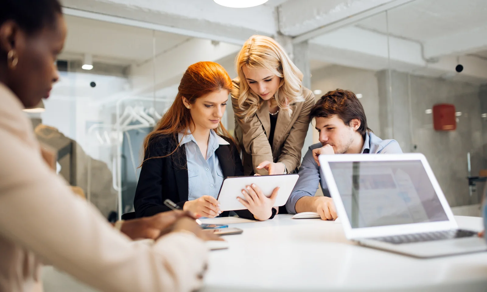 Group of professionals discussing business workflow improvements using a digital tablet in a modern office setting.