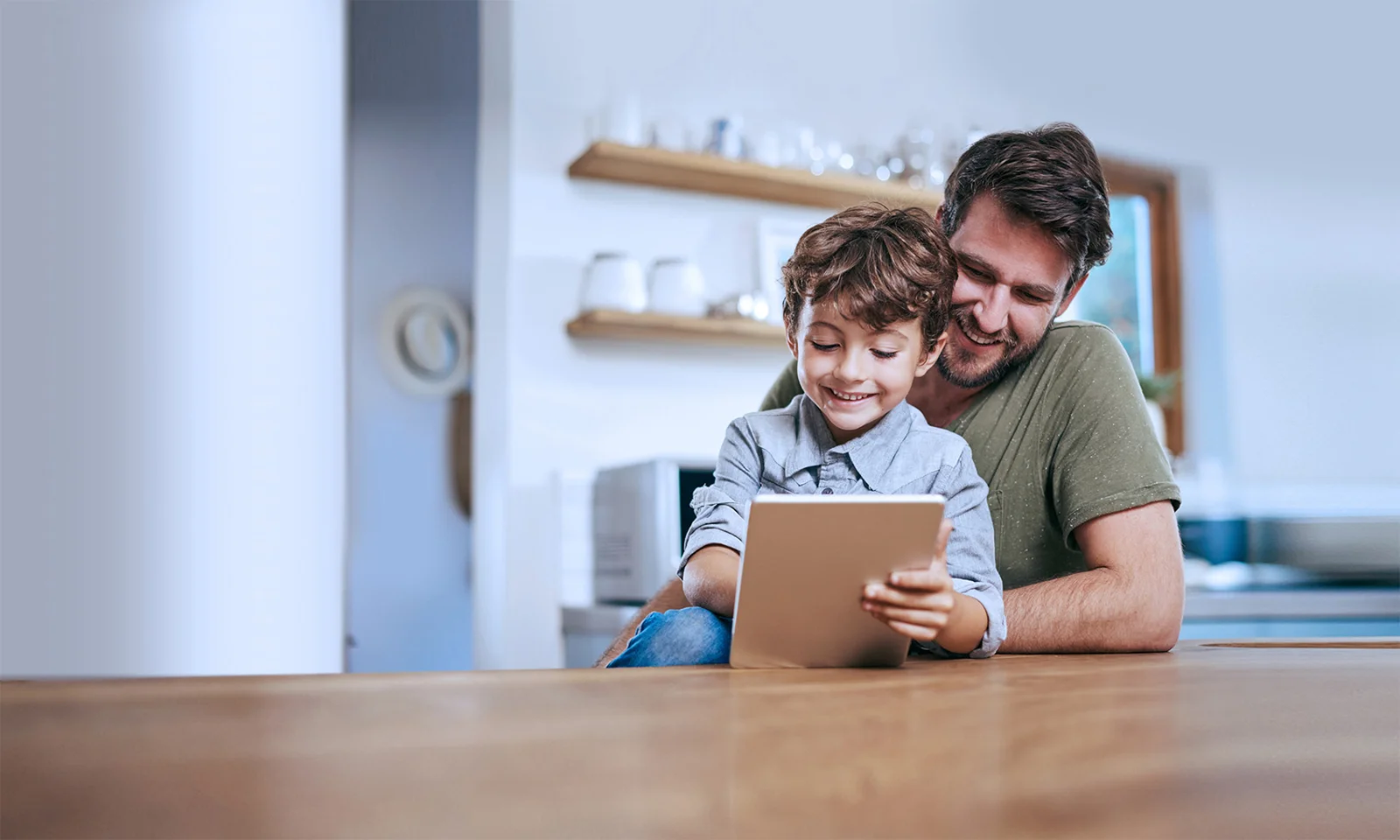 A smiling father and his young son enjoying time together using a tablet, illustrating a digital platform designed for children.