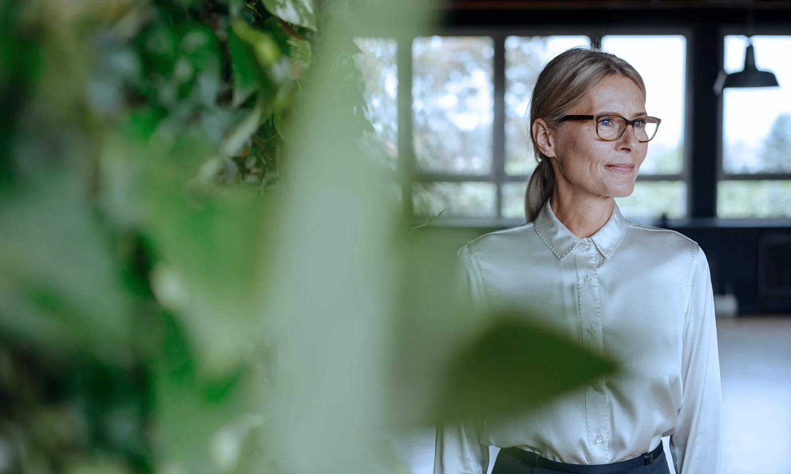 A confident professional woman in a light blouse, surrounded by greenery, symbolising CSR governance and leadership in sustainability