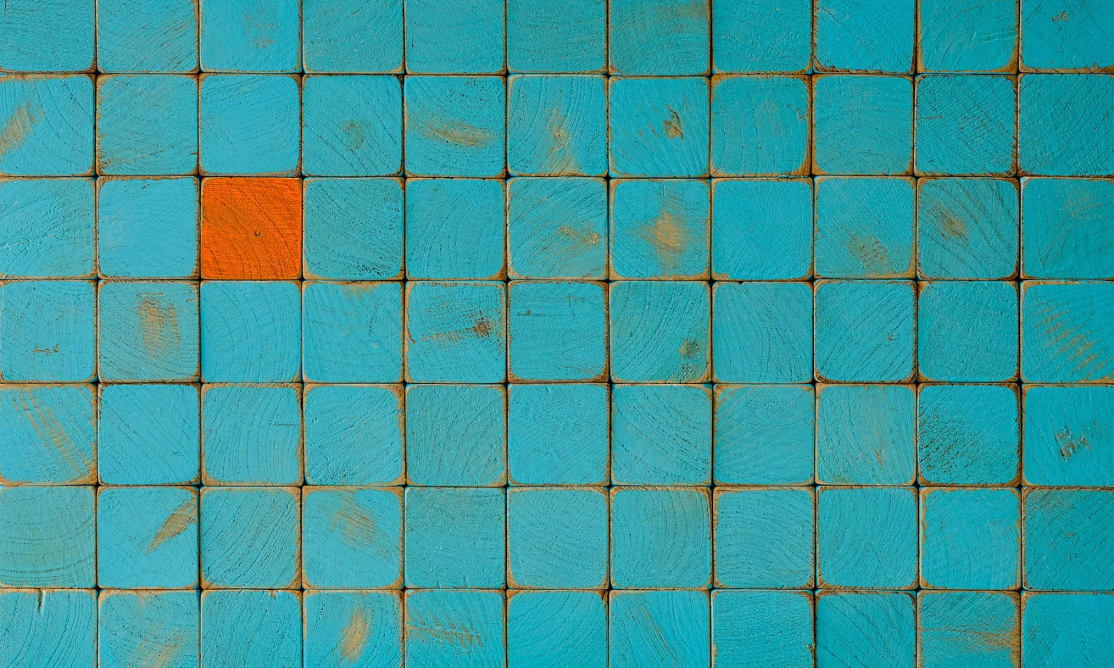 Pattern of blue wooden blocks with one orange block, symbolising innovation and differentiation.