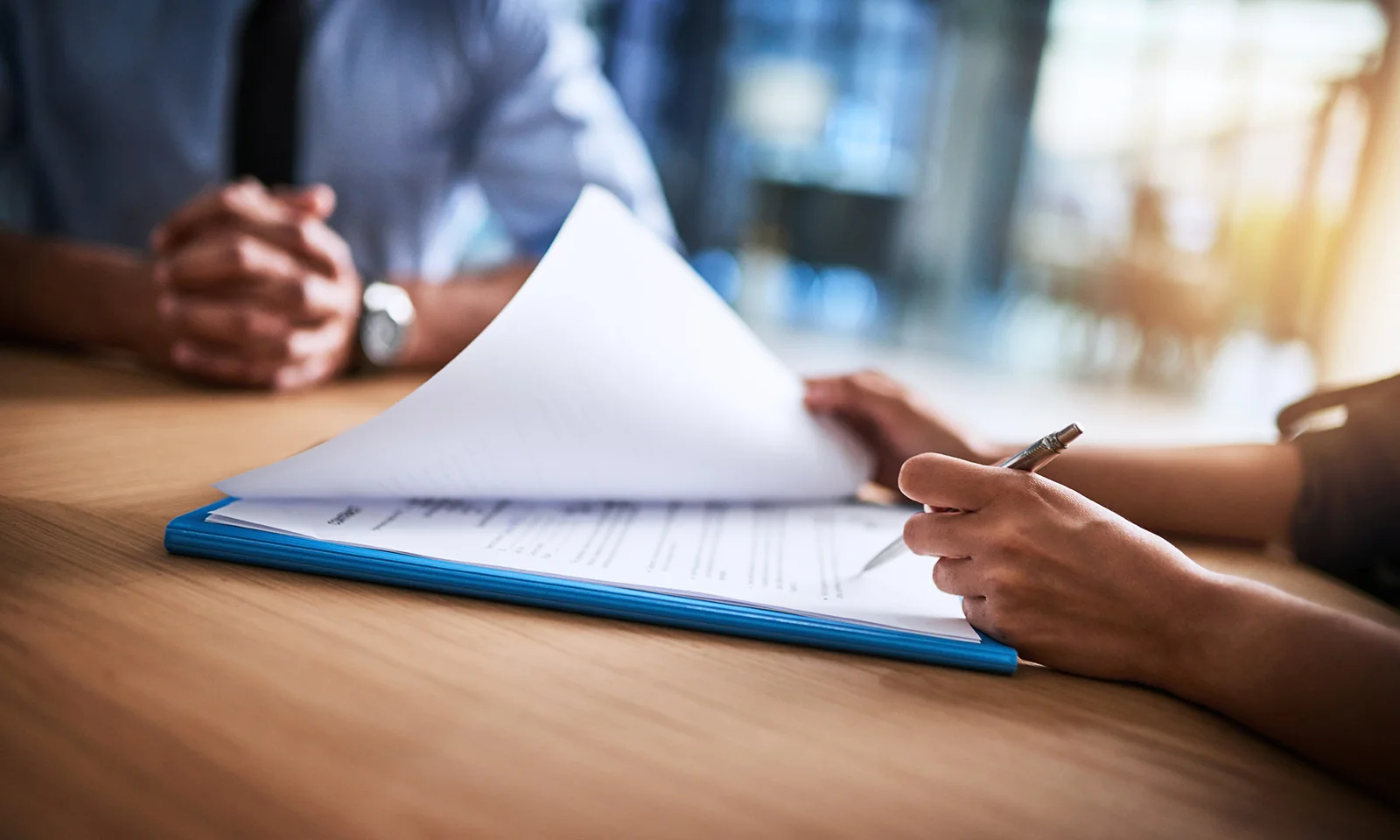 Close-up of hands reviewing a document with a pen, symbolising professional collaboration and careful consideration in decision-making.