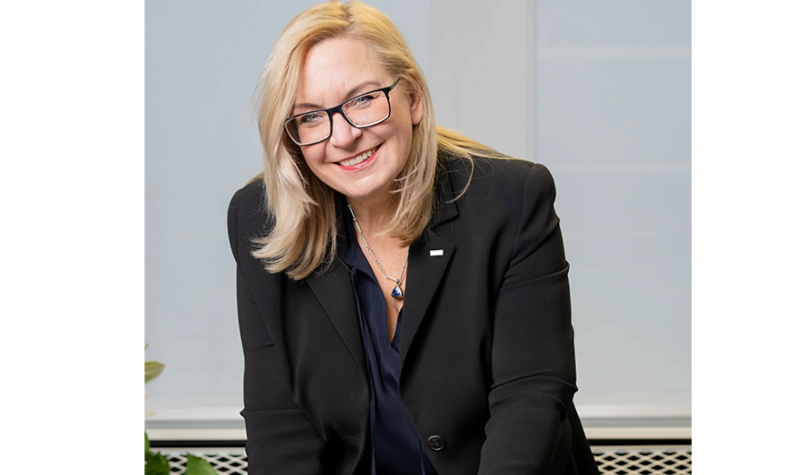 Marika Lulay, a member of the GFT Administrative Board, smiling warmly while leaning forward, wearing a black blazer and glasses, representing dynamic leadership and vision in the technology industry.