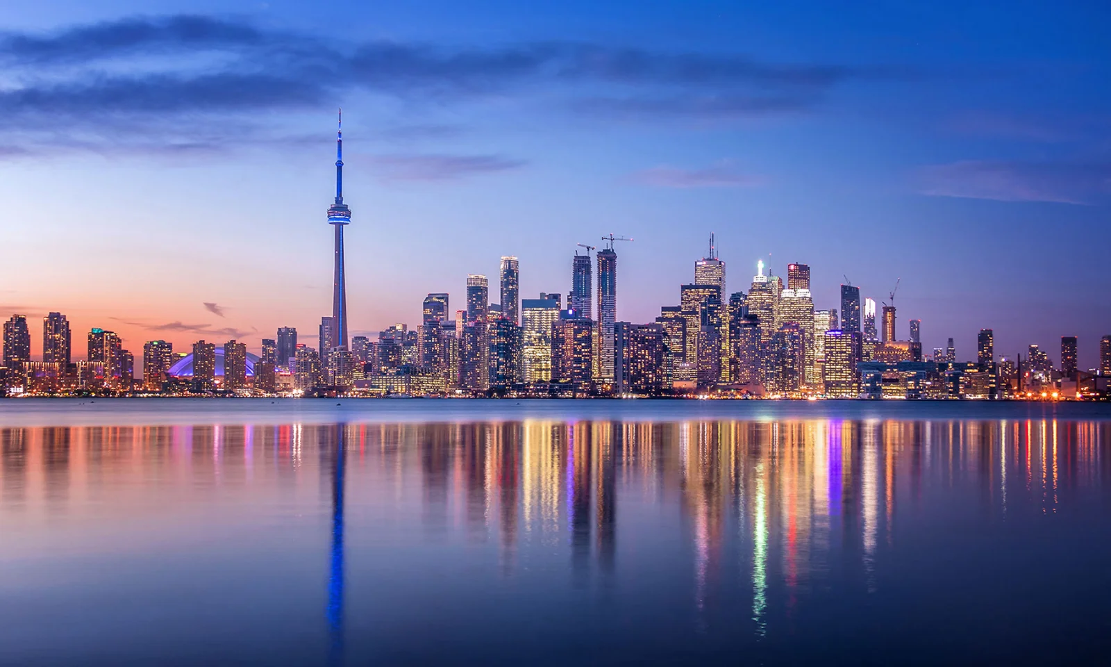 City skyline at dusk with reflections on the water, symbolizing stability and the future of the insurance industry.