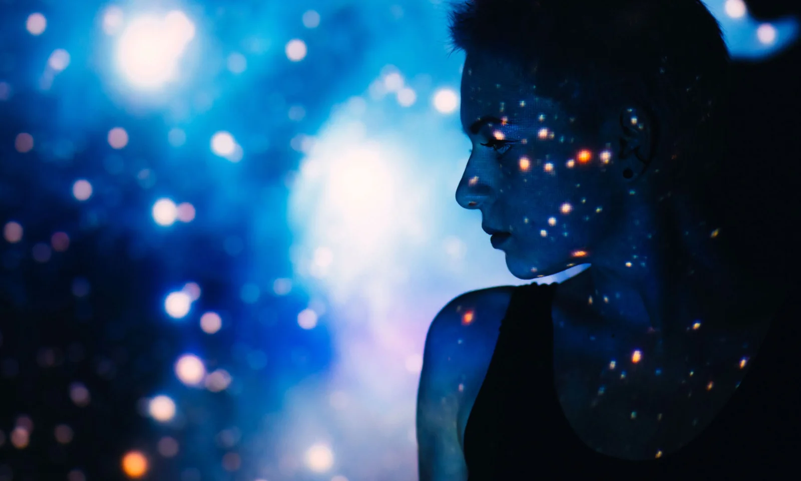 A silhouetted profile of a person with a digital starry projection on their face and background, symbolising the power and creativity of artificial intelligence.